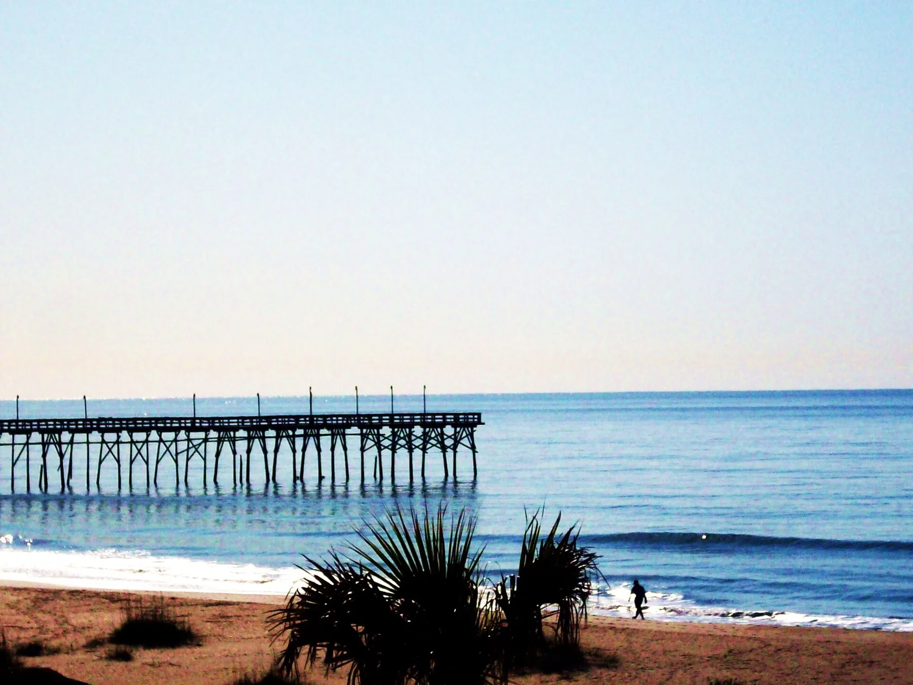 The Ocean Isle Beach fishing pier stretching out over the ocean, seen from the beach